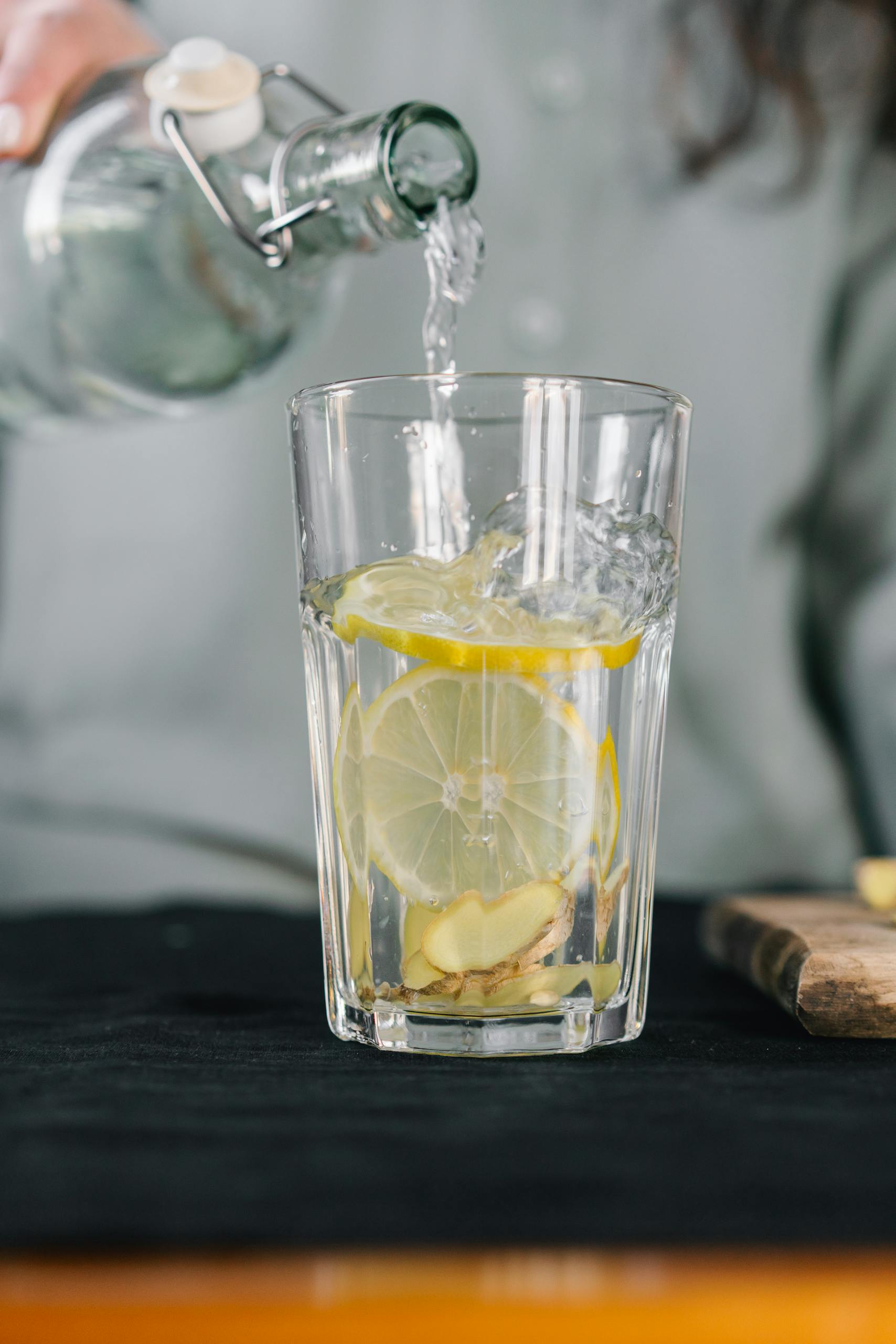 A glass of lemon water with ginger being poured for a refreshing detox drink.